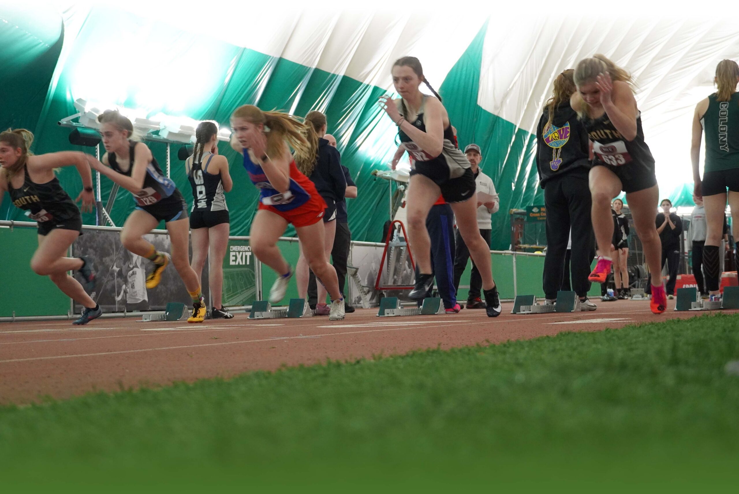 A group of track runners at the starting line inside the dome